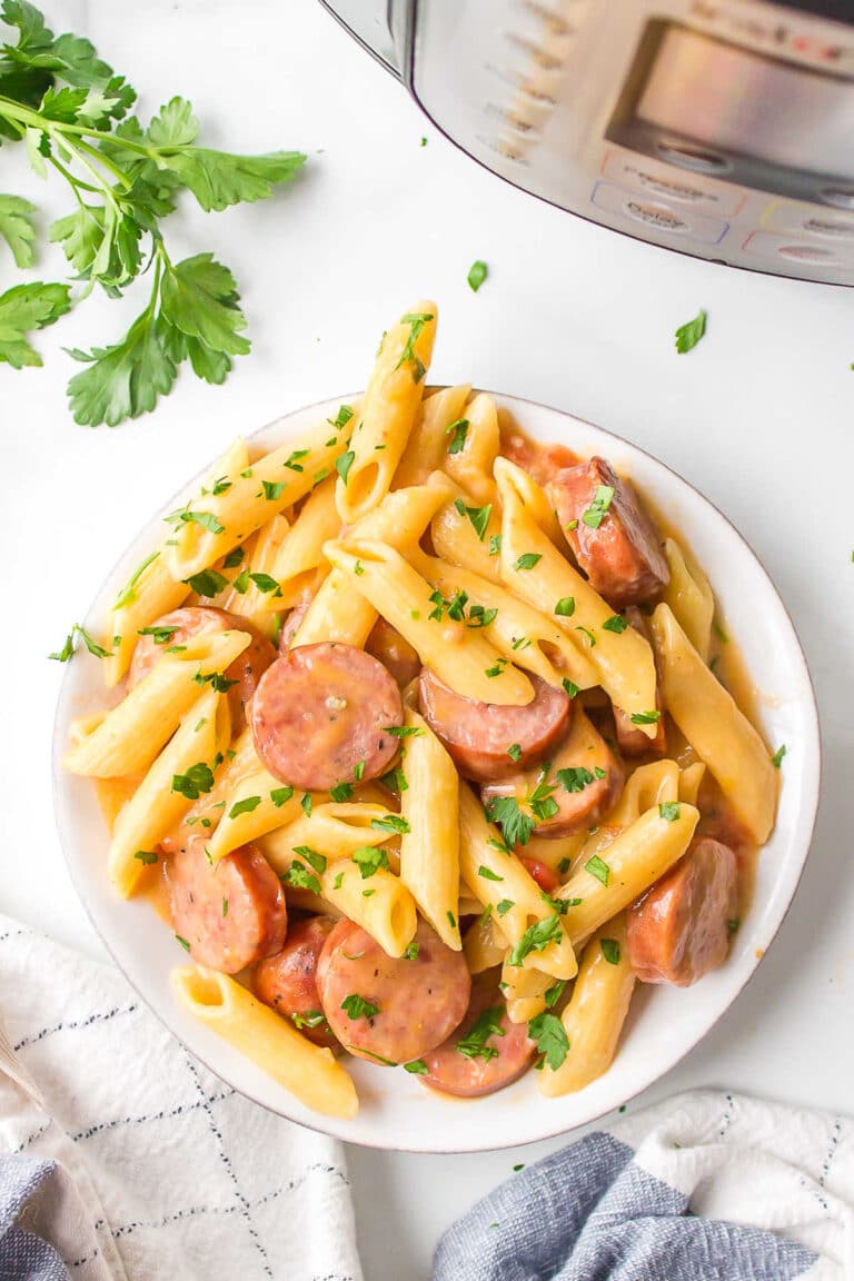 cheesy sausage pasta made in the Instant Pot served on a white plate and garnished with parsley