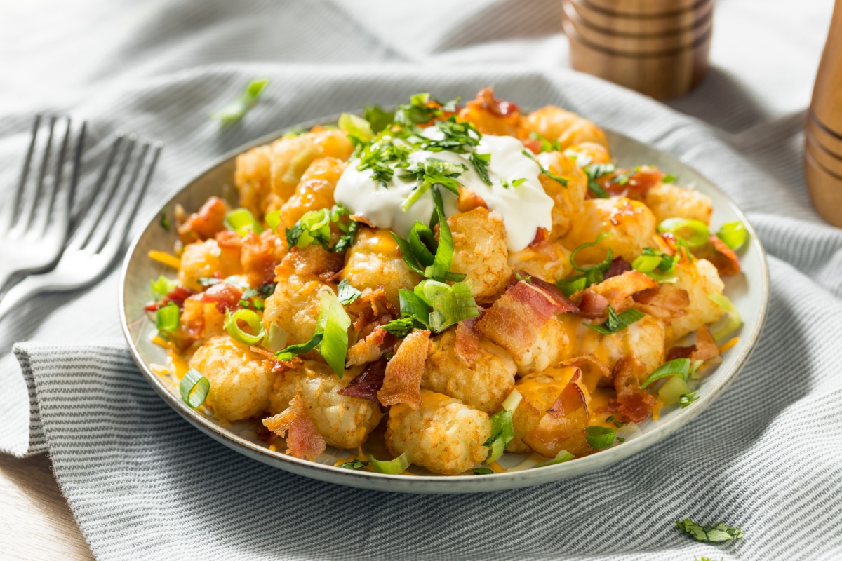 Air fry tater tots loaded with bacon, sour cream and sliced green onions.