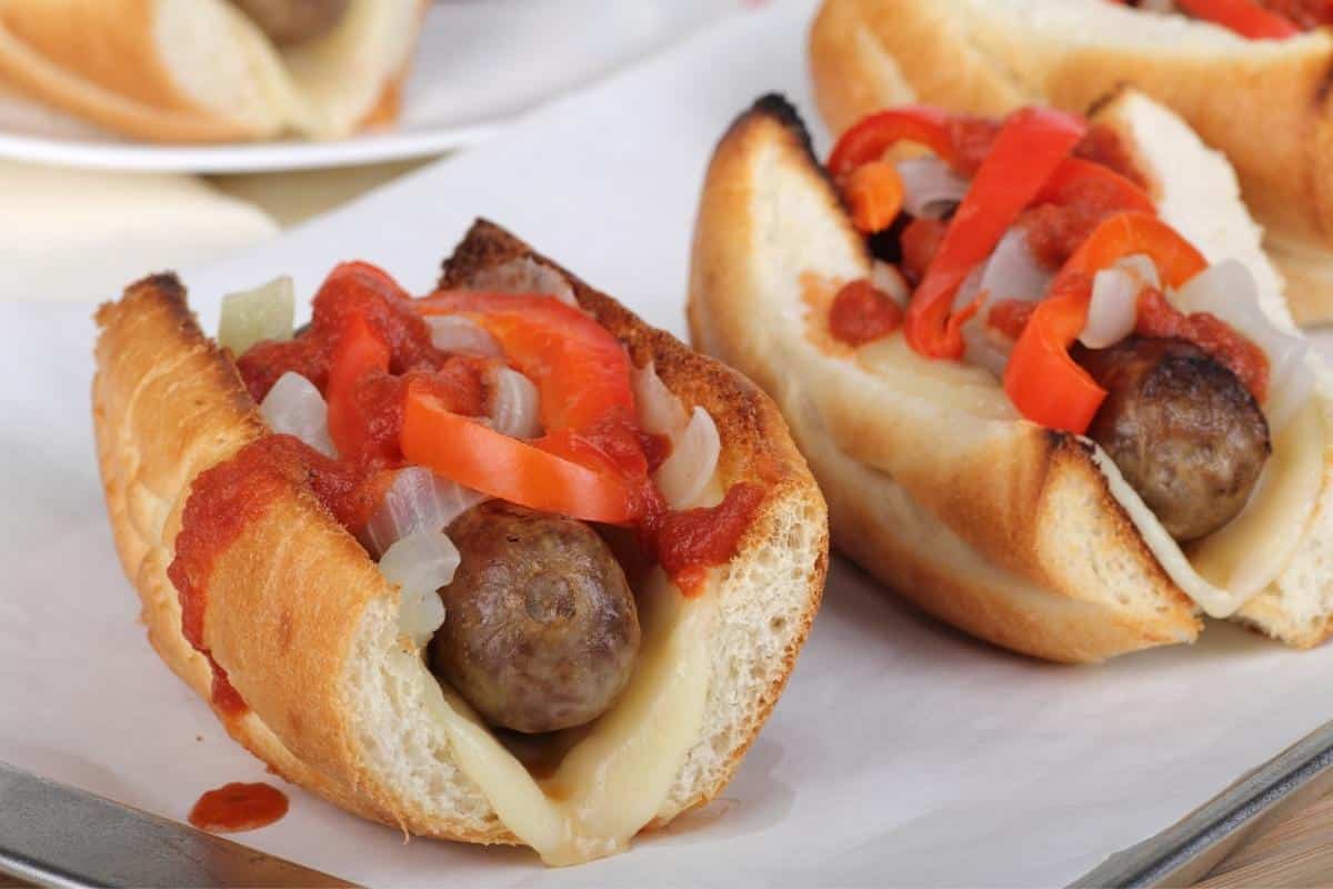 two air fryer brats on buns topped with red bell peppers