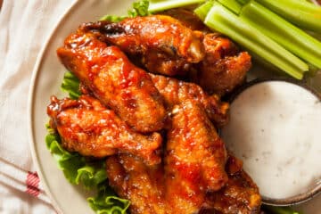 Air fryer chicken wings with buffalo sauce. An assortment of wings in served with celery stick and dressing for dipping.