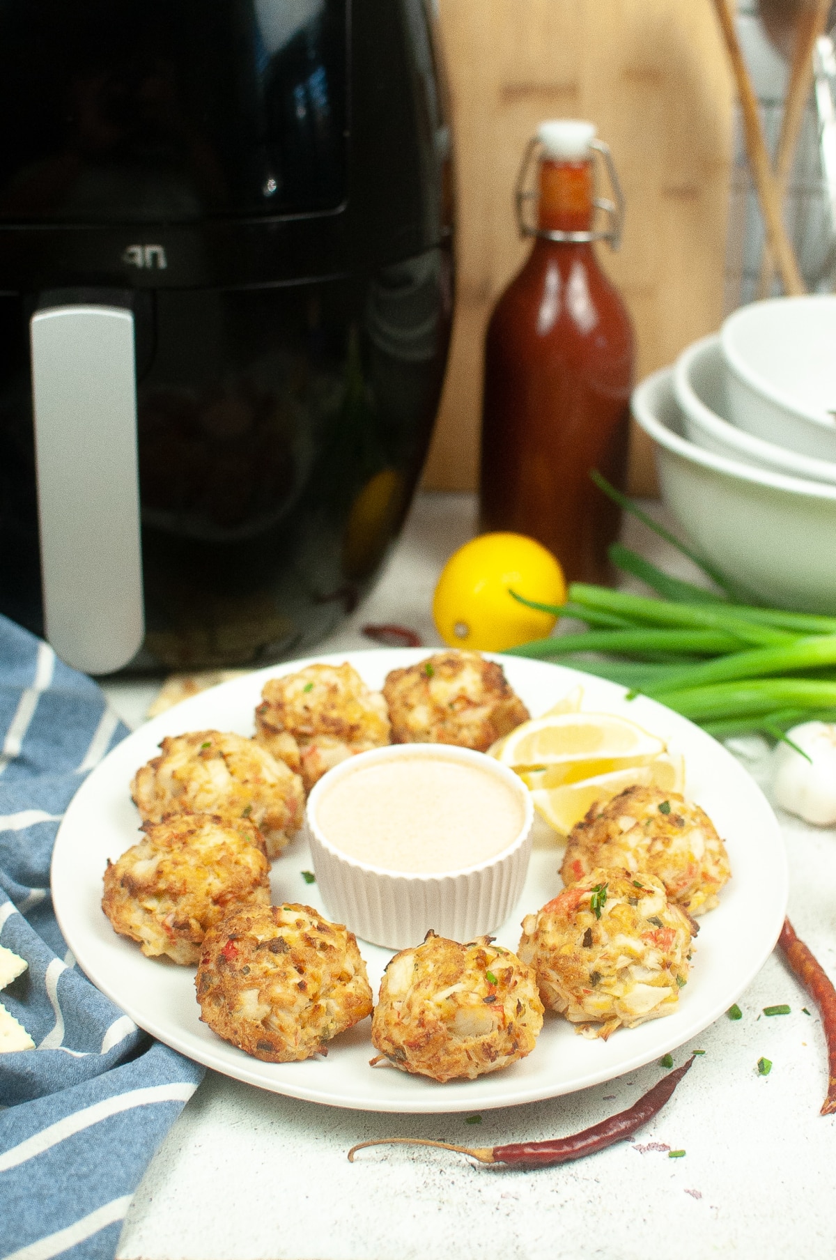 8 air fryer crab cakes arranged on a white plate with tartar sauce