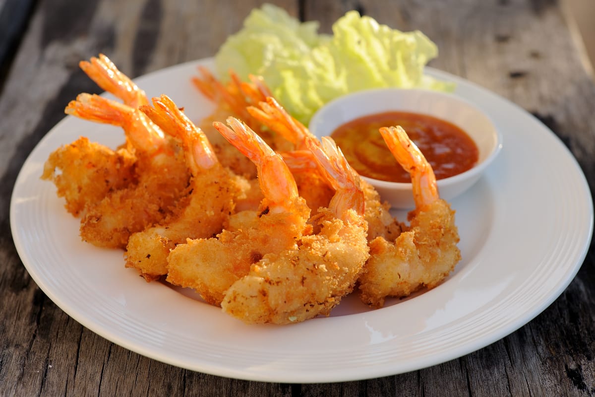 Air fryer shrimp served on a white platter with shrimp cocktail on the side.