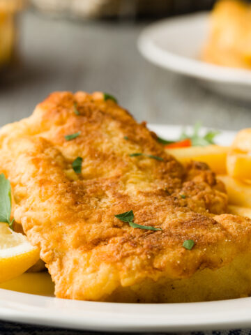 closeup of panko crusted baked cod with a lemon wedge and fries