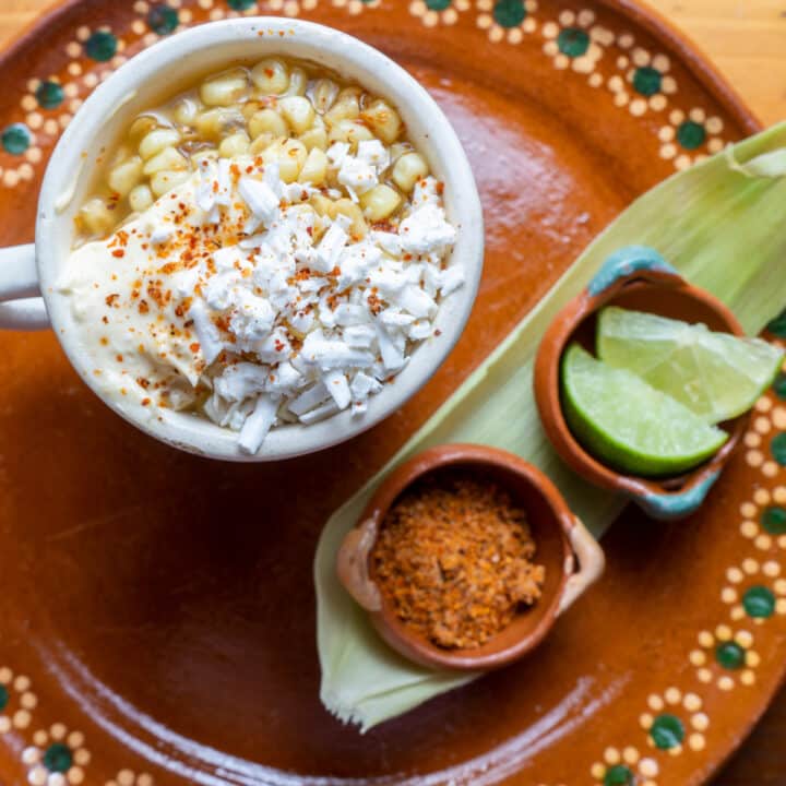 top down view of corn in a cup served with chili pepper and lime wedge on the side