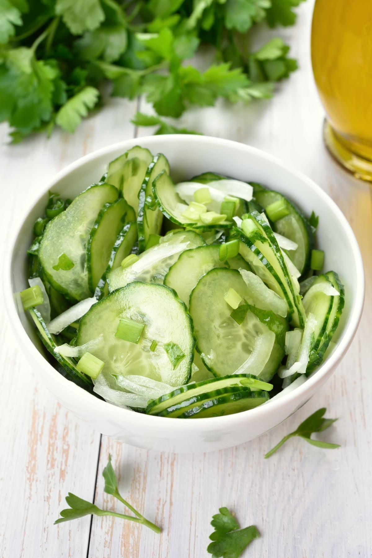 Portrait shot of old-fashioned cucumber, onion and vinegar salad on a white-washed wood background.