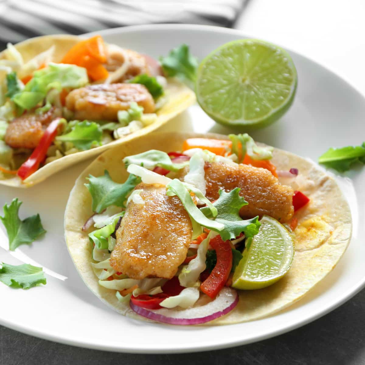 Fish Tacos with Sauce, coleslaw mix, onions and lime.