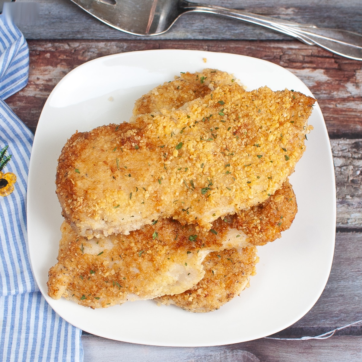 top down view of air fryer parmesan crusted chicken on a white plate