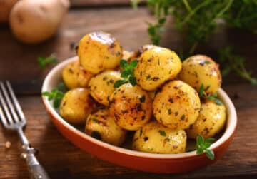Roasted Baby Potatoes with herbs served in a red bowl.