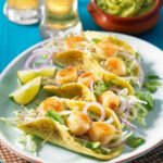 Pan Seared Scallops are wrapped in tortillas with a vegetable slaw and avocado sauce