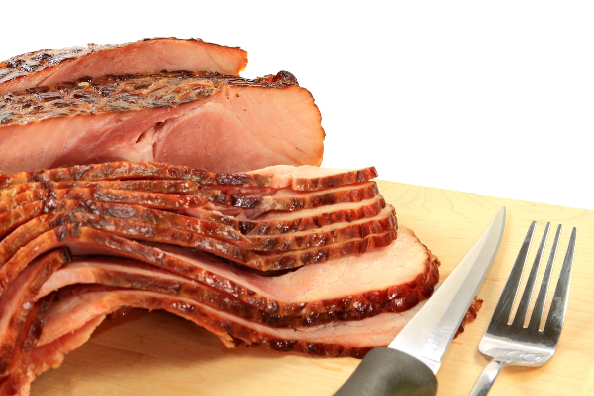 example of how to heat a fully cooked ham with carved slices on a cutting board ready to plate.
