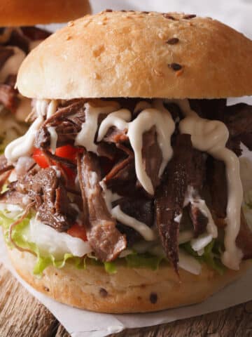 smoked chuck roast pulled and served on a bun. sandwich is drizzle with horseradish cream sauce.