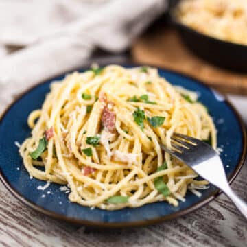Spaghetti Carbonara on plate with fork and skillet