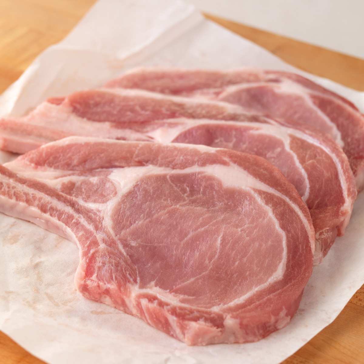 Raw bone-in pork chops ready for pan frying.